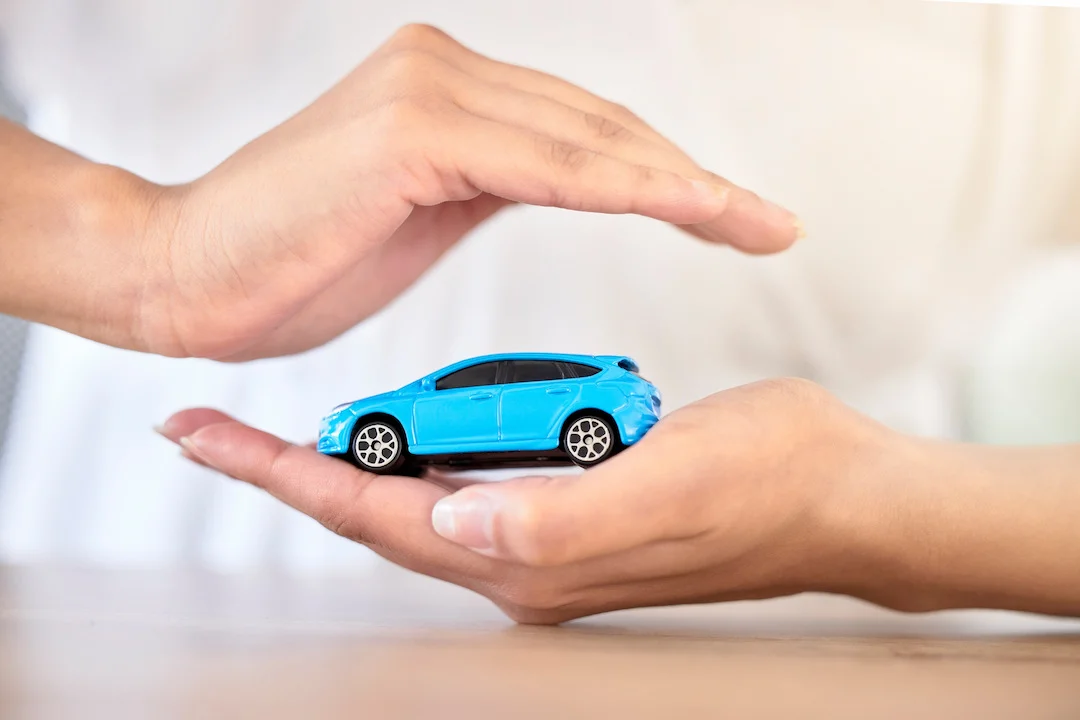 Manos protegiendo un automóvil azul